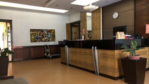 A reception area with a reception desk, a clock, a fire exit sign, and a painting on the wall. - Studio Apartment at Taguig Manila (Taguig)