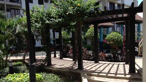 A courtyard with a pergola, brick steps, and various plants. - Studio Apartment at Taguig Manila (Taguig)