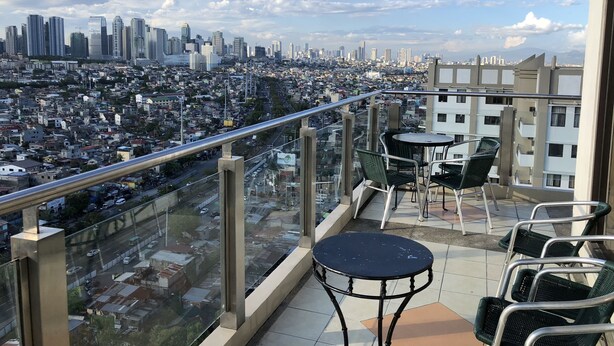 A balcony with a city view, including high-rise buildings and a densely packed urban area. - Studio Apartment at Taguig Manila (Taguig)