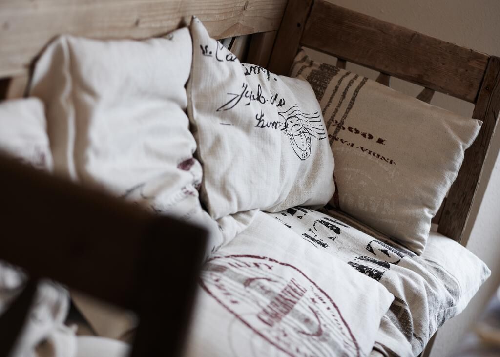 A bed with multiple pillows, some with text and designs, and a wooden headboard.