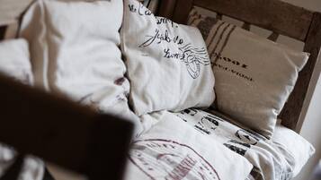A bed with multiple pillows, some with text and designs, and a wooden headboard.