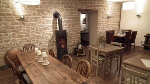 Un comedor rústico con pared de piedra, mesa y sillas de madera.