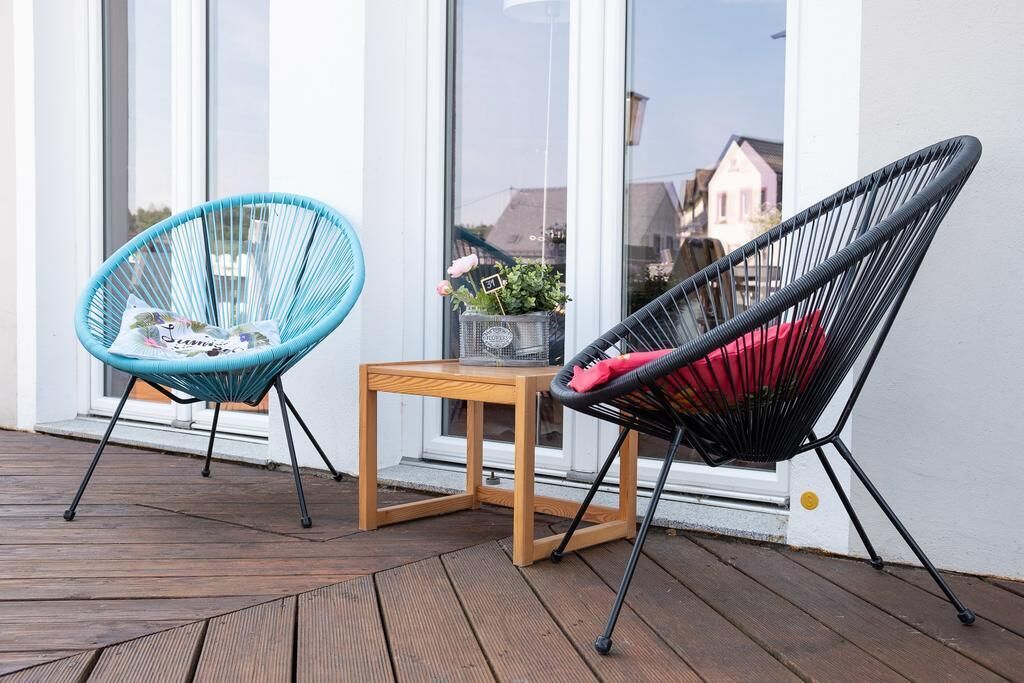 Two chairs on a wooden deck with a small table between them.