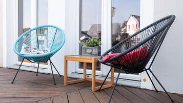 Two chairs on a wooden deck with a small table between them.