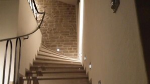 Una escalera con un fondo de pared de piedra e iluminación empotrada.