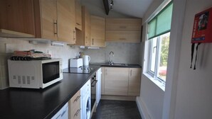 Une cuisine compacte dotée de meubles en bois, d’un four à micro-ondes, d’un évier et d’une fenêtre offrant une vue agréable.