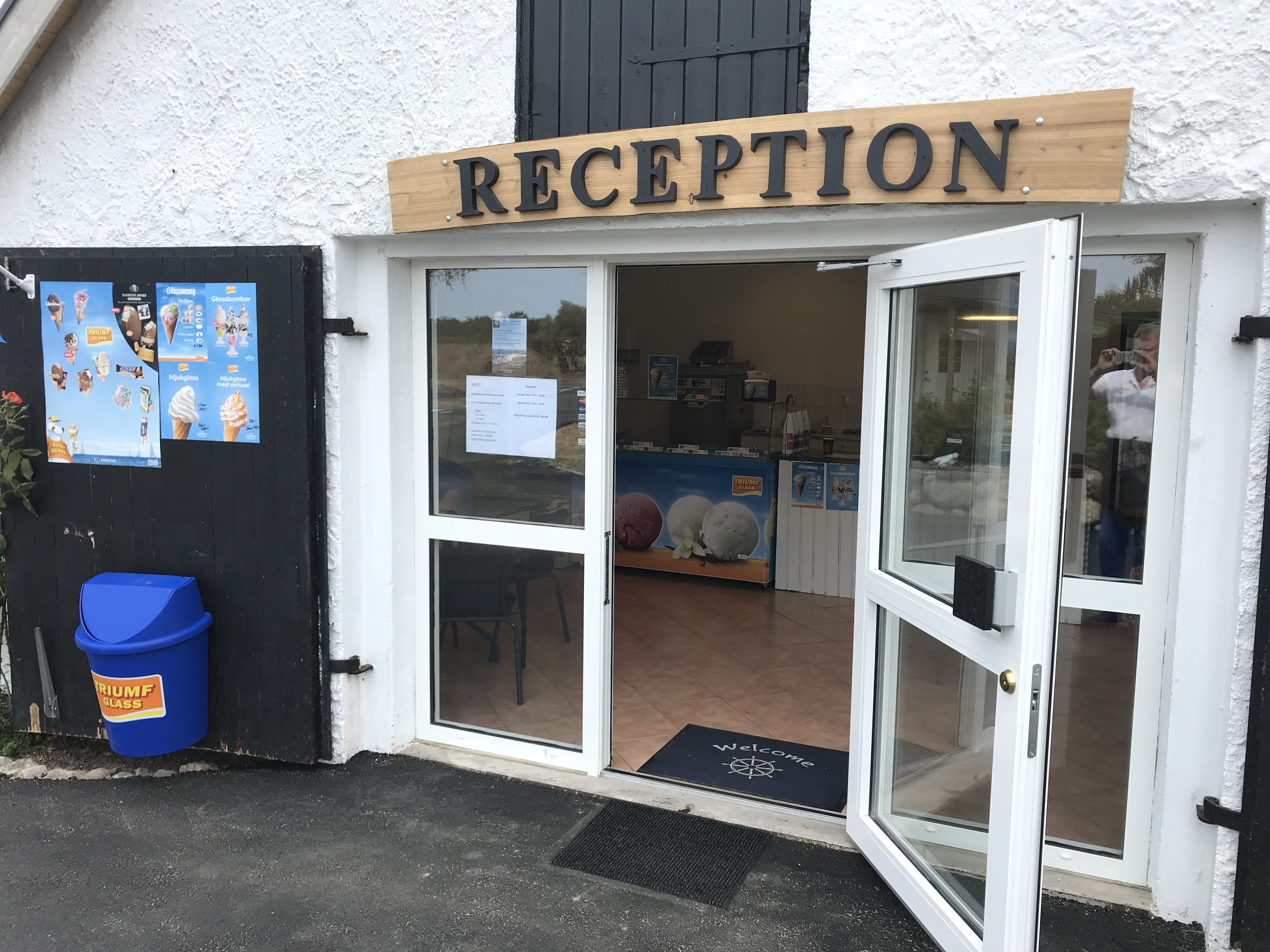 A reception area with a wooden sign, a glass door, and a welcome mat.