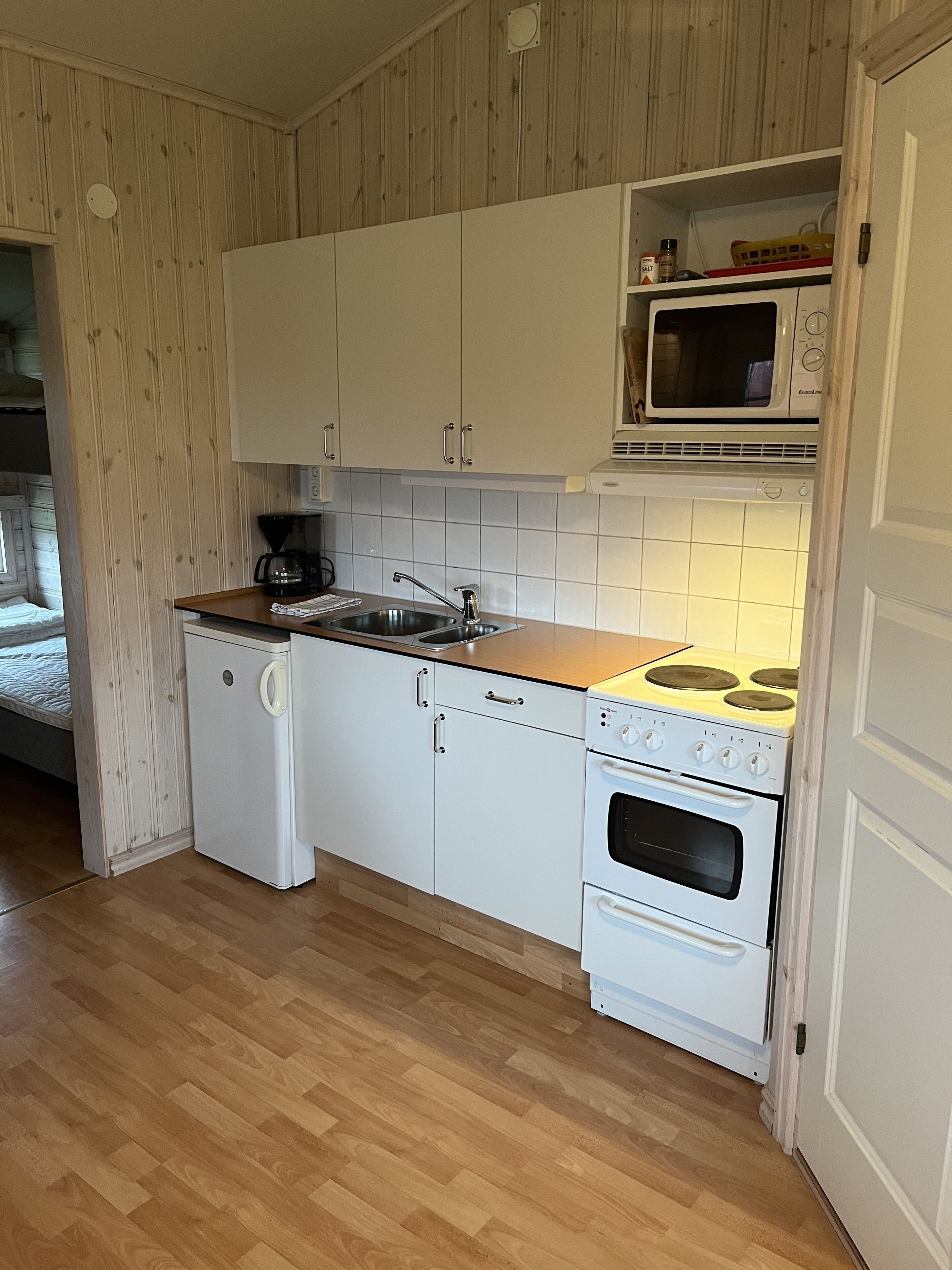 A compact kitchen with white cabinets, a built-in microwave, a stove, and a dishwasher.