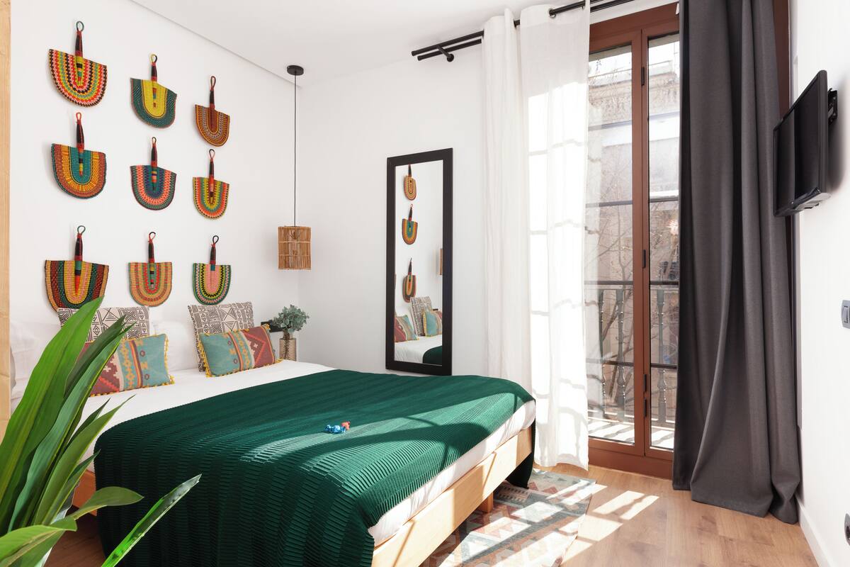 Ein Schlafzimmer mit einem Bett, einem großen Spiegel und Blick ins Freie.