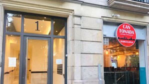A building with a large glass entrance, a visible number "1" on the door, and a sign reading "CAN TONADA CAFETERIA & RESTAURANTE BARCELONA". - Casa Vaganto (Barcelona)