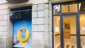 A building entrance with a large advertisement for a cash point service. - Casa Vaganto (Barcelona)