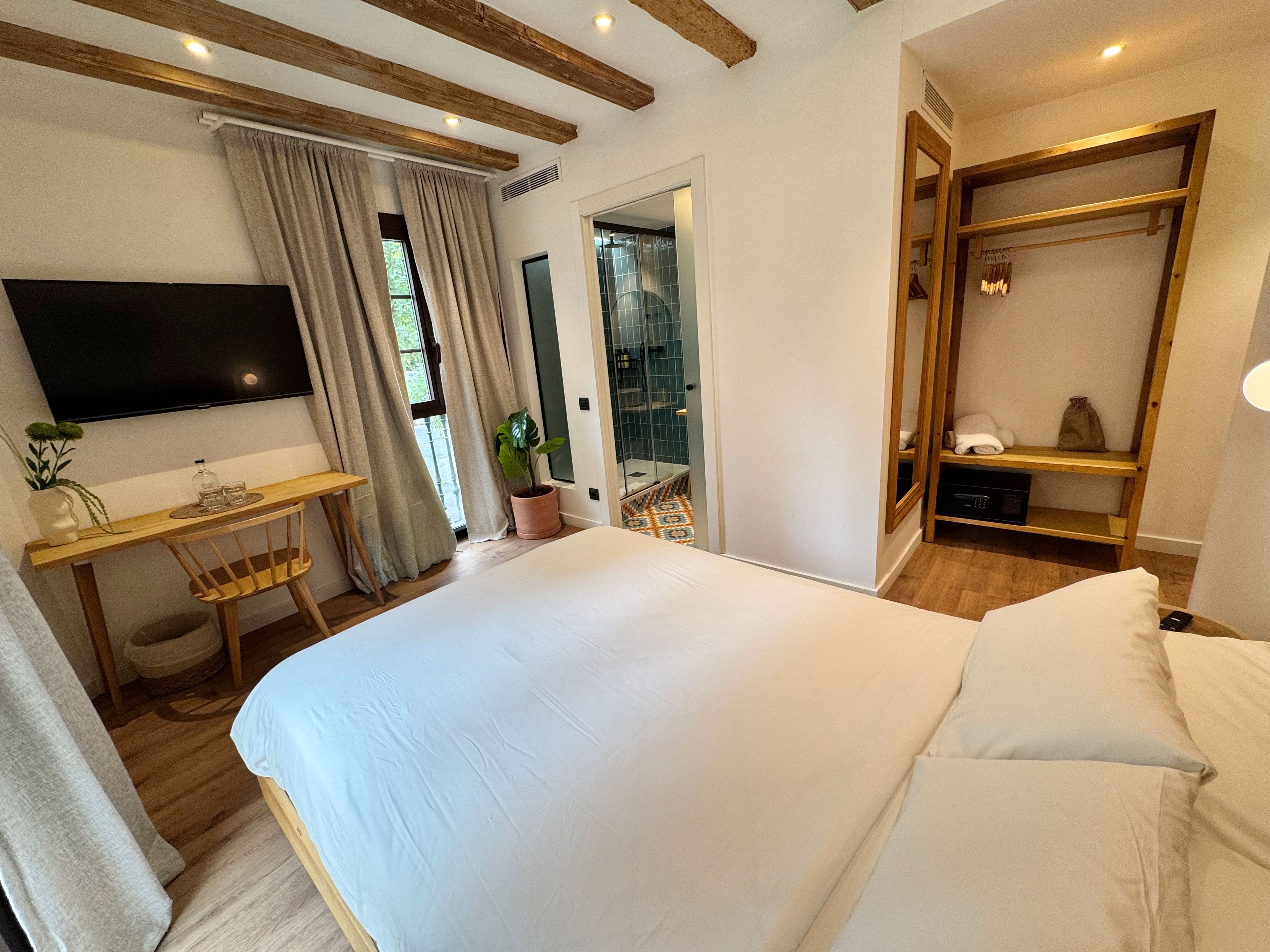 Un dormitorio con una cama grande, un escritorio de madera, un televisor y un vestidor.