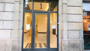 A building entrance with a glass door marked with the number 1. - Casa Vaganto (Barcelona)