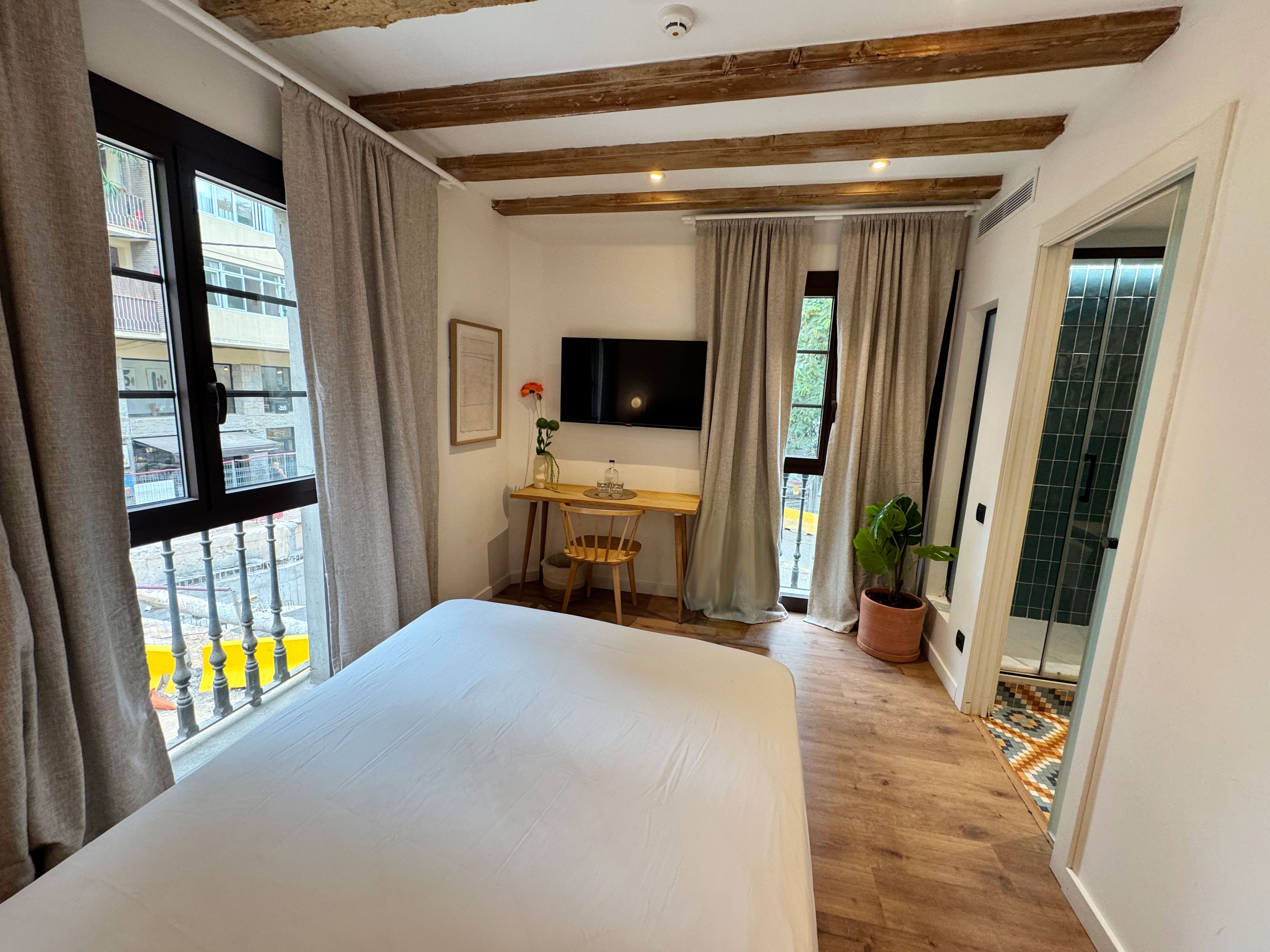 Een hotelkamer met een bed, een bureau, een televisie en uitzicht op het balkon.