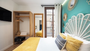 A bedroom with a bed, a wooden wardrobe, a television, and a balcony view. - Casa Vaganto (Barcelona)