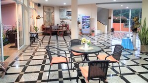 A hotel lobby with a checkered floor, seating area with tables and chairs, a sofa, and a staircase leading to an upper level. - Khao Saming Paradise Resort (Khao Saming)