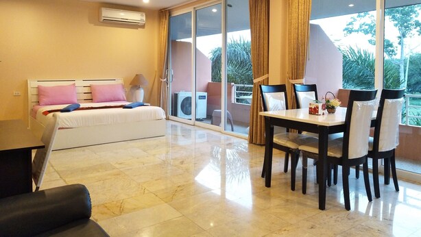 A hotel room with a bed, a dining table with chairs, and a large sliding glass door leading to a balcony. - Khao Saming Paradise Resort (Khao Saming)