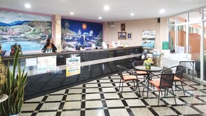 A reception area with a check-in counter, a mural, a seating area with tables and chairs, and a large window. - Khao Saming Paradise Resort (Khao Saming)