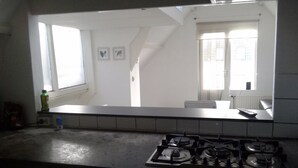 A kitchen with a gas stove, a window, and a view of a staircase. - MyCityLofts - Schiedamseweg (Rotterdam)