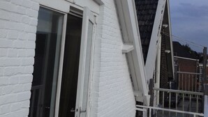 A white brick building with a sloped roof and a balcony. - MyCityLofts - Schiedamseweg (Rotterdam)