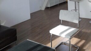 A modern, spacious room with a sloped ceiling, a dining area with a bar, and a large window providing natural light. - MyCityLofts - Schiedamseweg (Rotterdam)