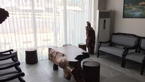 Una sala de estar moderna con un ventanal grande, una mesa de centro de madera, un sofá y un cuadro en la pared.
