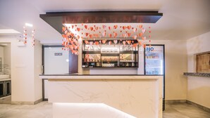 Un área de recepción con mostrador de mármol, un letrero para personal autorizado, un refrigerador y estantes con diversos artículos.