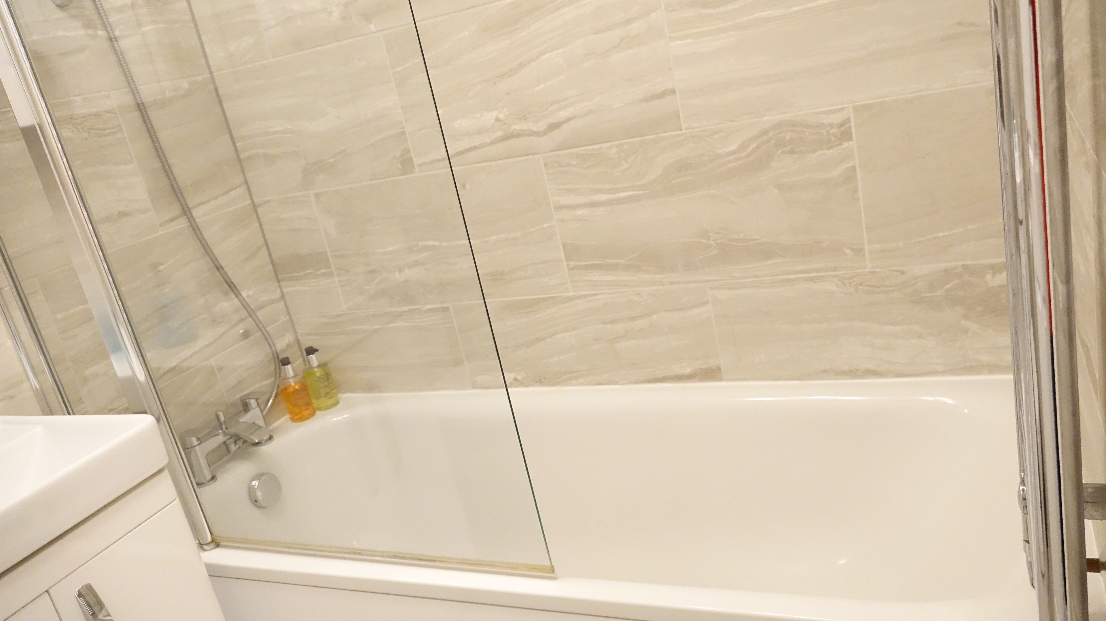 A modern bathroom with a glass-enclosed shower, a white bathtub, and a white sink.