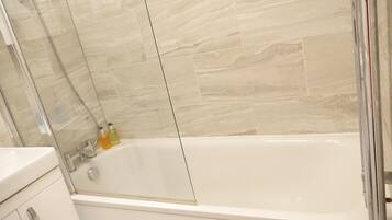 Un baño moderno con ducha de vidrio, una bañera blanca y un lavabo blanco.