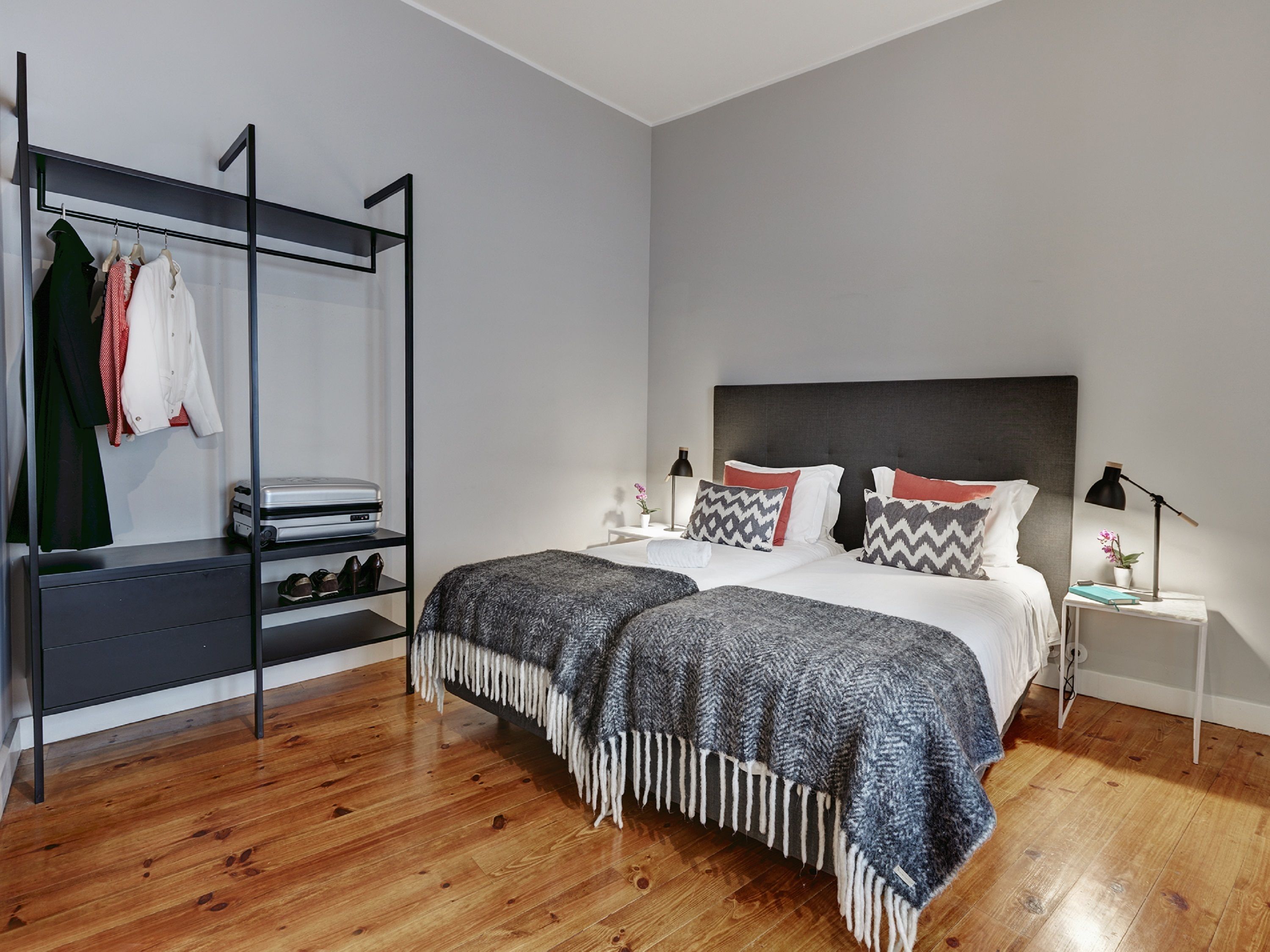 A modern bedroom with a bed, bedside tables, a wardrobe, and a shoe rack.