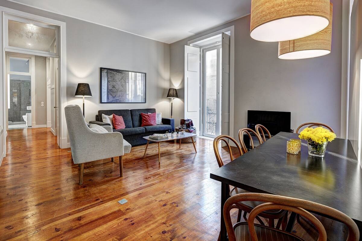 A modern living room with a sofa, chairs, a dining table, and a TV.
