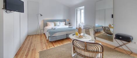 A modern bedroom with a bed, bedside table, lamp, chair, and a suitcase.