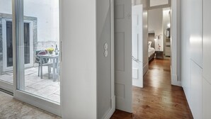 Un intérieur moderne avec une porte coulissante en verre donnant sur un balcon, un plancher en bois et un design minimaliste.