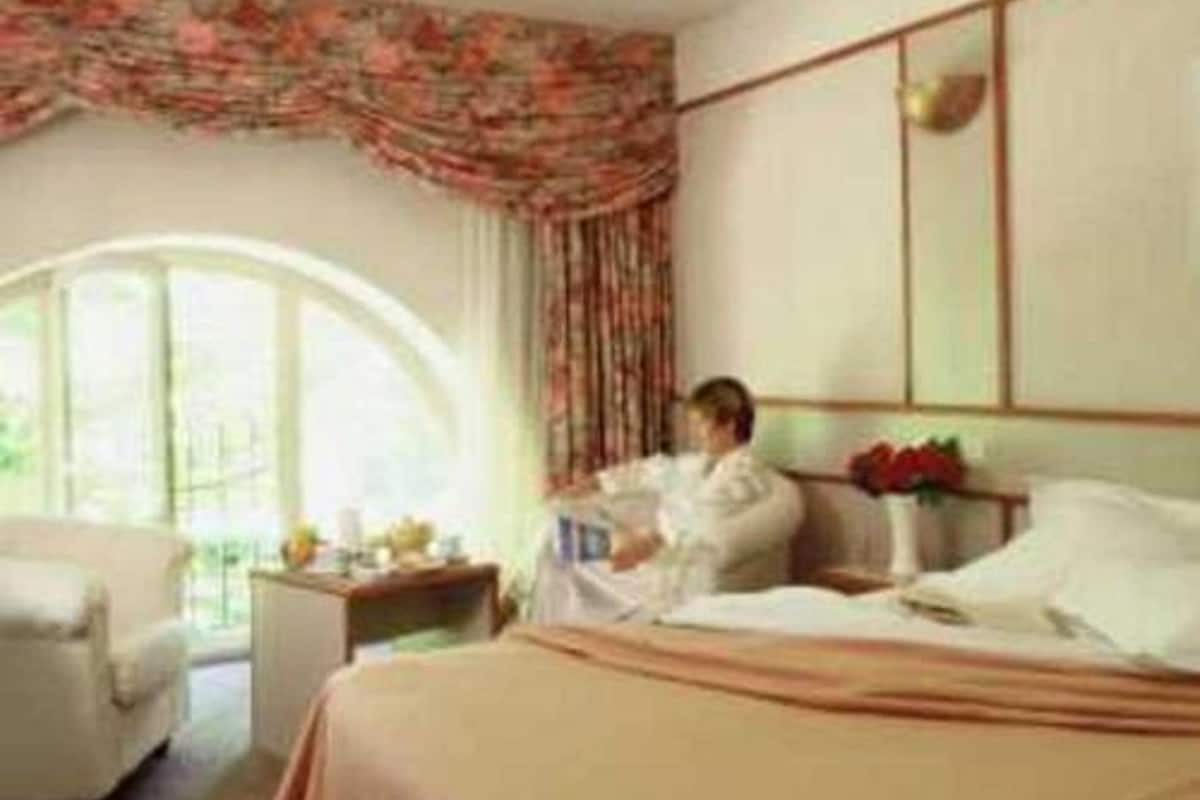 Une chambre d’hôtel avec un lit, une table de chevet, une chaise et une fenêtre avec des rideaux.