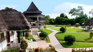 Een resort met gebouwen met rieten daken, een verzorgd gazon en een zwembad.