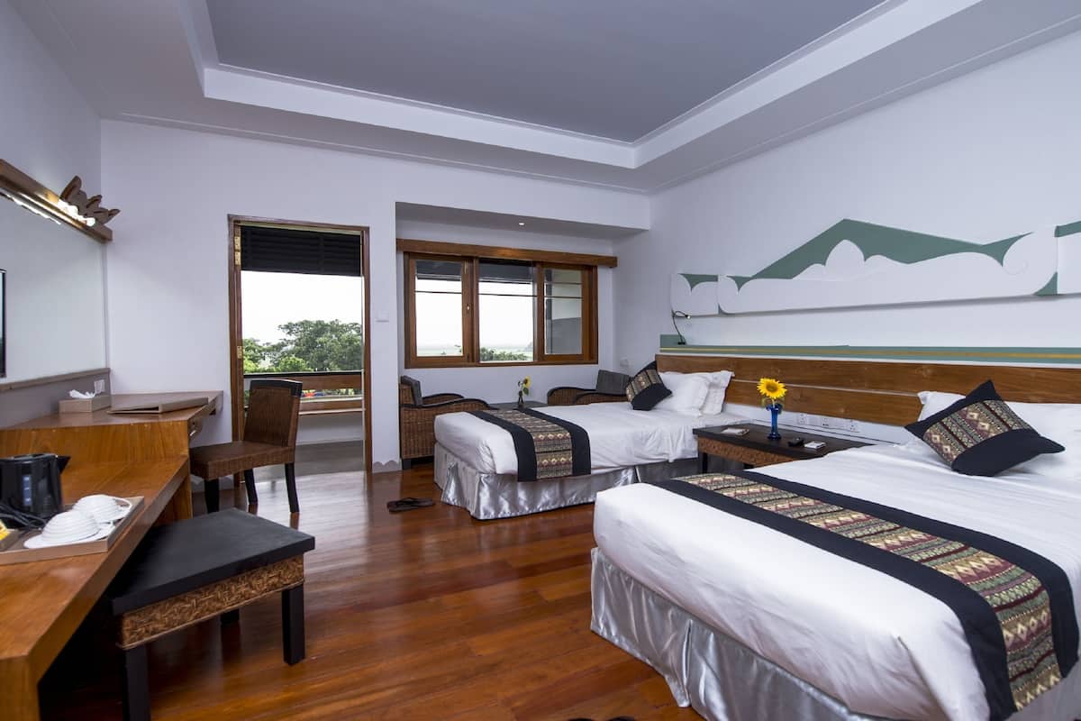 Quarto de hotel com duas camas, uma escrivaninha e uma cadeira. Há uma janela com vista para o exterior.