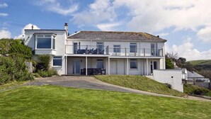 A two-story house with a balcony, a front porch, and a well-maintained lawn. - Green Door - Upper Tregudda (Port Isaac)