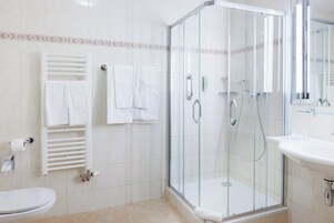 Un bagno moderno con cabina doccia in vetro, lavandino bianco e water.
