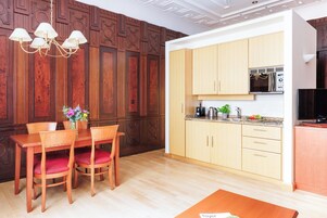 Cozinha moderna com armários de madeira, micro-ondas embutido e área de refeições com mesa e cadeiras de madeira.