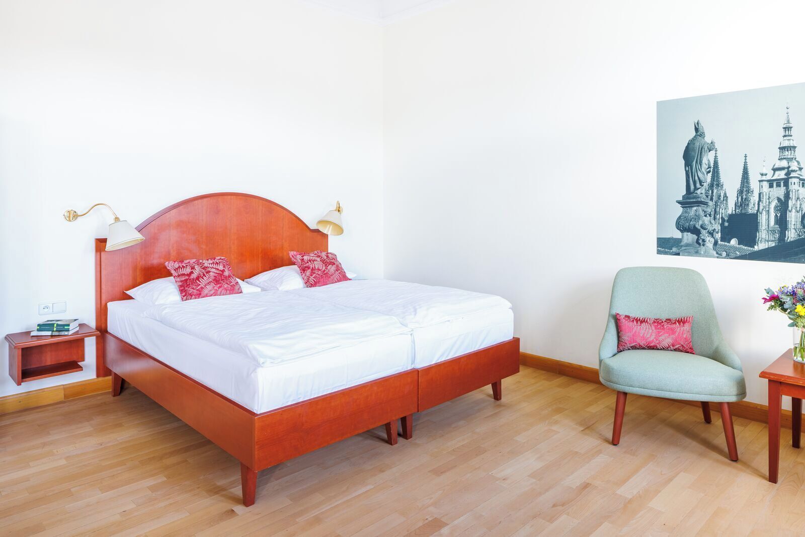 Un lit double avec une tête de lit en bois, deux tables de chevet, une chaise et un tableau accroché au mur.