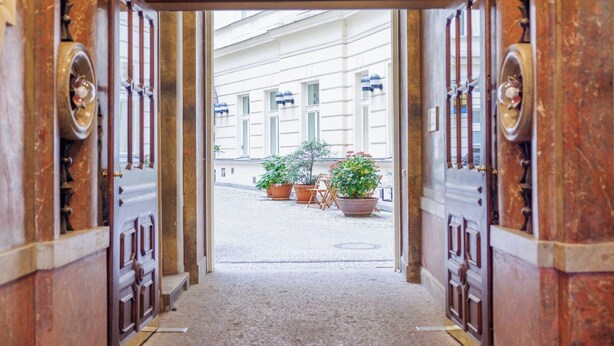 An ornate doorway leading to a courtyard with potted plants and a building in the background. - Hapimag Resort Prague (Prague)