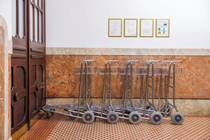 Um quarto com parede de mármore, portas de madeira e um carrinho de metal com rodas.