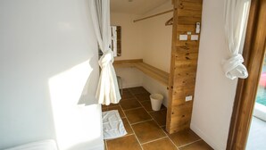 Un baño con un banco de madera, una toalla blanca y un cubo blanco en el suelo.