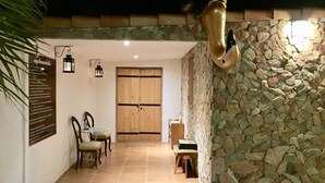 Un patio exterior acogedor con un muro de piedra, una puerta de madera y una zona de comedor con sillas y una mesa.
