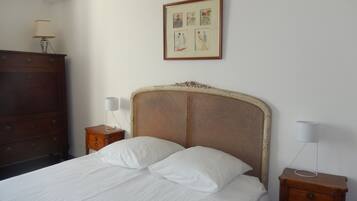 A bedroom with a bed, two bedside tables, a dresser, and a framed picture on the wall.