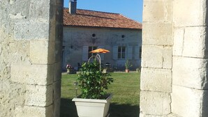 Un arc donnant accès à un bâtiment doté d’un toit en tuiles et d’une plante en pot placée au premier plan.