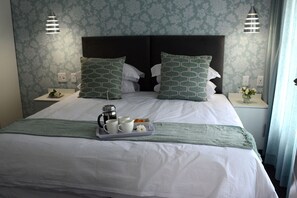 A neatly made bed with a tray of breakfast items, two nightstands with lamps, and patterned wallpaper. - Touch of Class Villas (Pretoria)