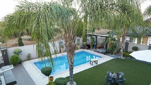 A backyard with a swimming pool, a lawn, and a patio area with outdoor furniture. - Cycad Palm Boutique Guest House (Gaborone)