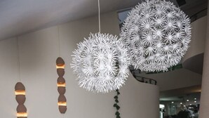 Una sala moderna con un sofá púrpura, jarrones decorativos y lámparas esféricas únicas.