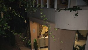 Un edificio de varios niveles con una escalera central, rodeado de vegetación y una zona de recepción.